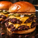 Featured photo of juicy smash burgers on the griddle with melted cheese, crispy beef patties, pickles, and toasted buns.